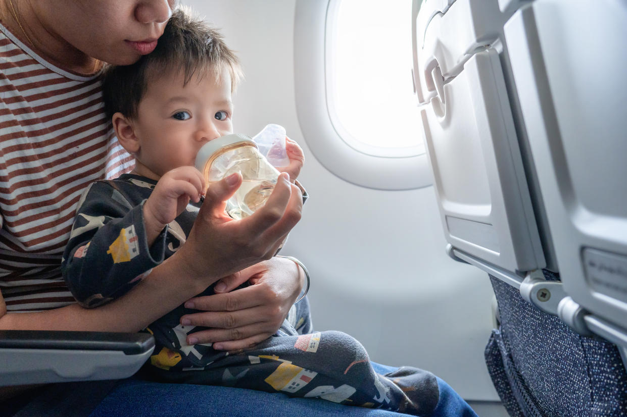 An adult in an airplane seat holding a baby on their lap.