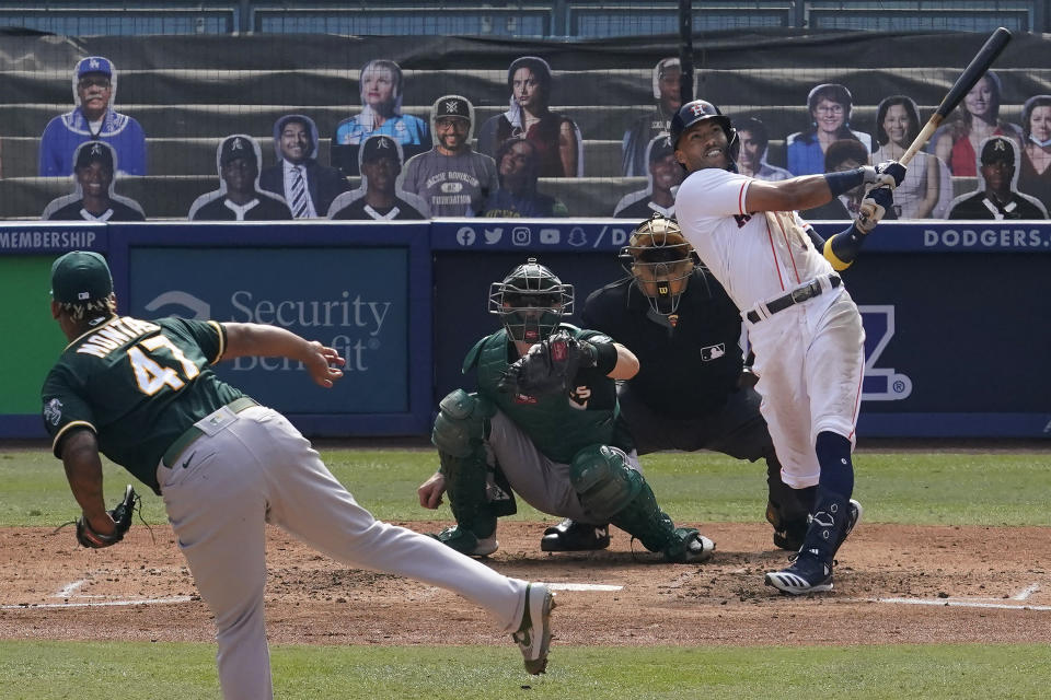 Houston Astros' Carlos Correa, right, hits a three-run home run off of Oakland Athletics pitcher Frankie Montas, left, during the fourth inning of Game 4 of a baseball American League Division Series in Los Angeles, Thursday, Oct. 8, 2020. (AP Photo/Marcio Jose Sanchez)