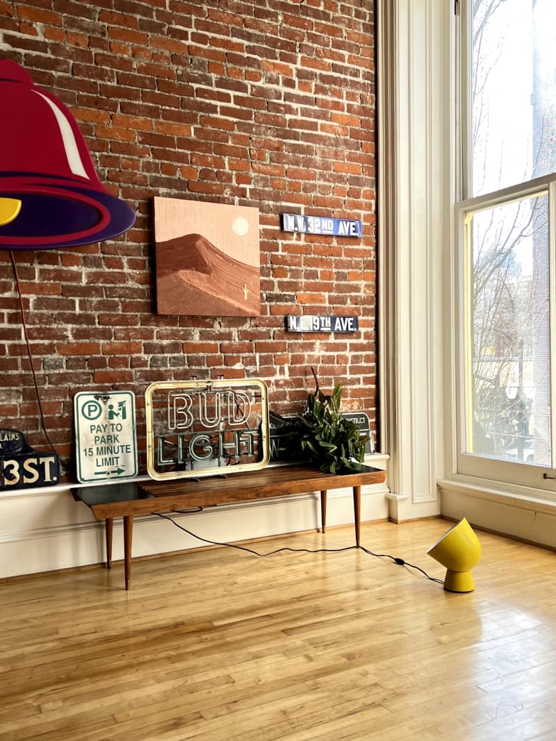 Wooden bench along exposed brick wall with sign art in loft.