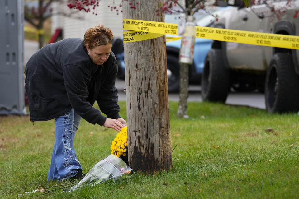 A woman places flowers outside the crime scene tape at Schemengees Bar & Grille, Sunday, Oct. 29, 2023, in Lewiston, Maine. The community is working to heal following mass shootings at the bar and a bowling alley in Lewiston on Wednesday, Oct. 25. (AP Photo/Matt Rourke)