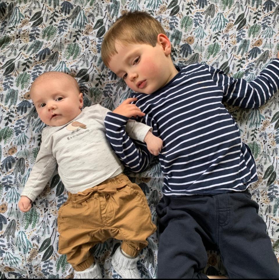 Alex and his sibling laying on a bed. 