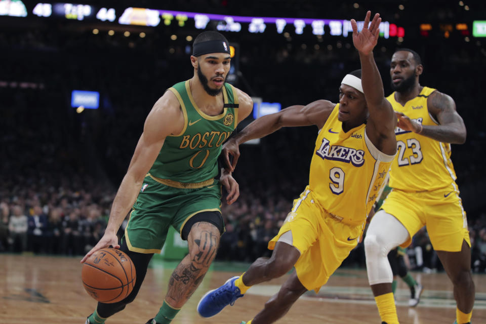 El alero de los Celtics de Boston Jayson Tatum ataca el canasto ante la defensa del base de los Lakers de Los Ángeles Rajon Rondo y del alero LeBron James, en la primera mitad del juego del lunes 20 de enero de 2020, en Boston. (AP Foto/Charles Krupa)