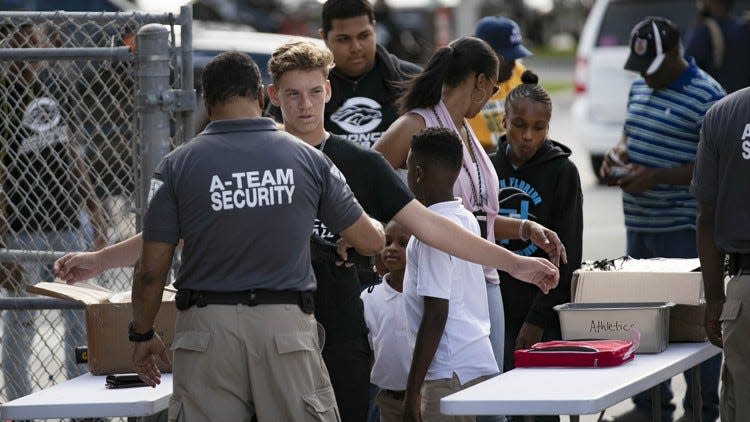 People entering the Palm Beach Central High School stadium are checked with a metal detector in Wellington in 2018. The Palm Beach County school district has approved a $2.25 million contract for mobile metal detectors at all county high schools.