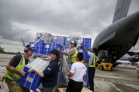 Air crew and volunteers unload aid from a Royal Australian Air Force (RAAF) transport plane carrying donated aid for Myanmar's flood victims at Yangon international airport in Yangon on August 10, 2015. REUTERS/Soe Zeya Tun