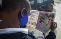 A man reads a copy of The Standard newspaper with coverage of the two-hour appearance of Britain's Prince Harry and Meghan with Oprah Winfrey, in Nairobi, Kenya Tuesday, March 9, 2021. Prince Harry and Meghan's explosive TV interview divided people around the world on Monday, rocking an institution that is struggling to modernize with claims of racism and callousness toward a woman struggling with suicidal thoughts. (AP Photo/Sayyid Abdul Azim)