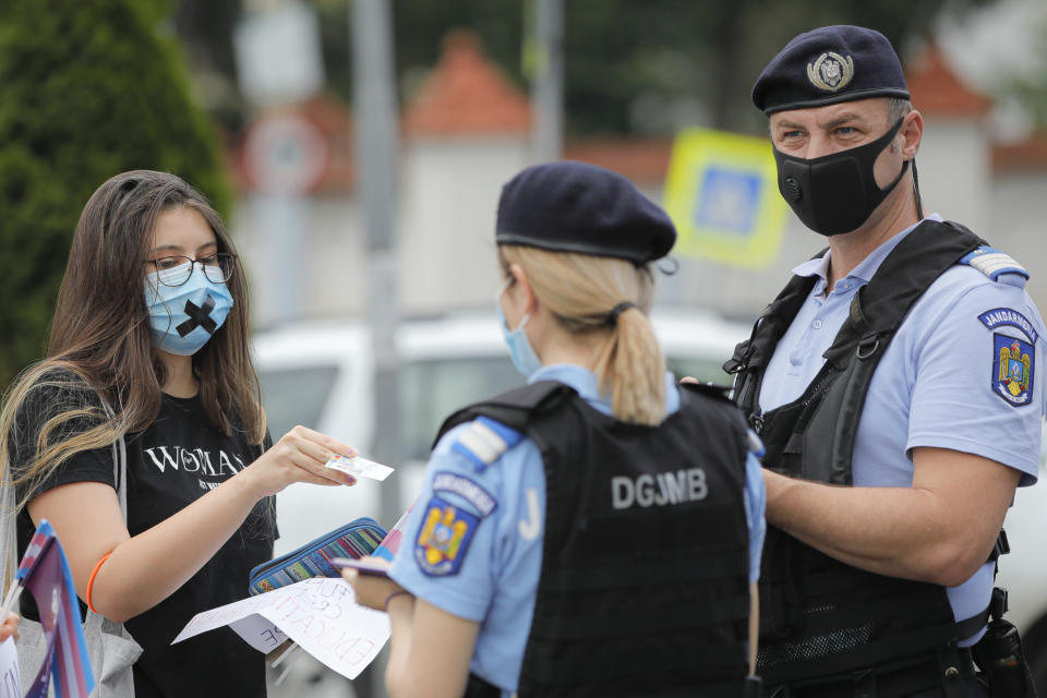 A protester holds identity papers as gendarmes check participants outside the presidential palace in Bucharest, Romania, Thursday, June 18, 2020, during a rally against a law banning the teaching of gender studies. Dozens of protesters gathered outside Bucharest's Cotroceni Presidential Palace, to express their opposition to a law banning the teaching of gender studies in the country's schools and universities and call on President Klaus Iohannis to reject signing the bill and send it back to parliament. (AP Photo/Vadim Ghirda)