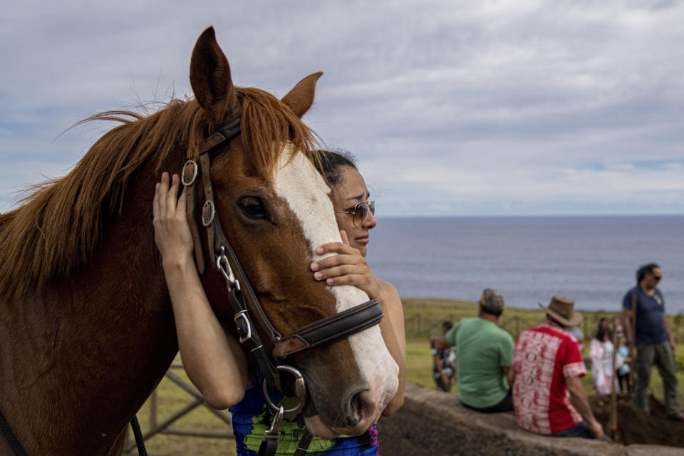 Valeria Salfate abraza a Rusio, el caballo que perteneció a su difunto amigo Emilio Araki durante su entierro en el cementerio de Hanga Roa, Rapa Nui o Isla de Pascua, Chile, el sábado 26 de noviembre de 2022. (Foto AP/Esteban Félix)