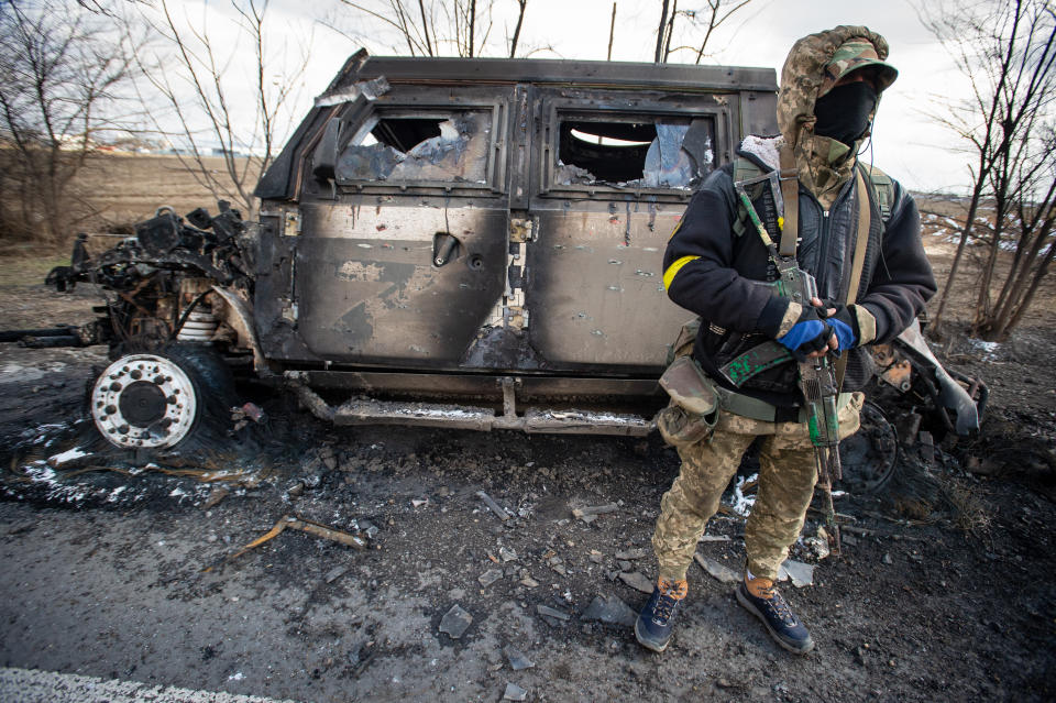 Ukrainischer Soldat neben einem ausgebrannten russischem Militär-Fahrzeug