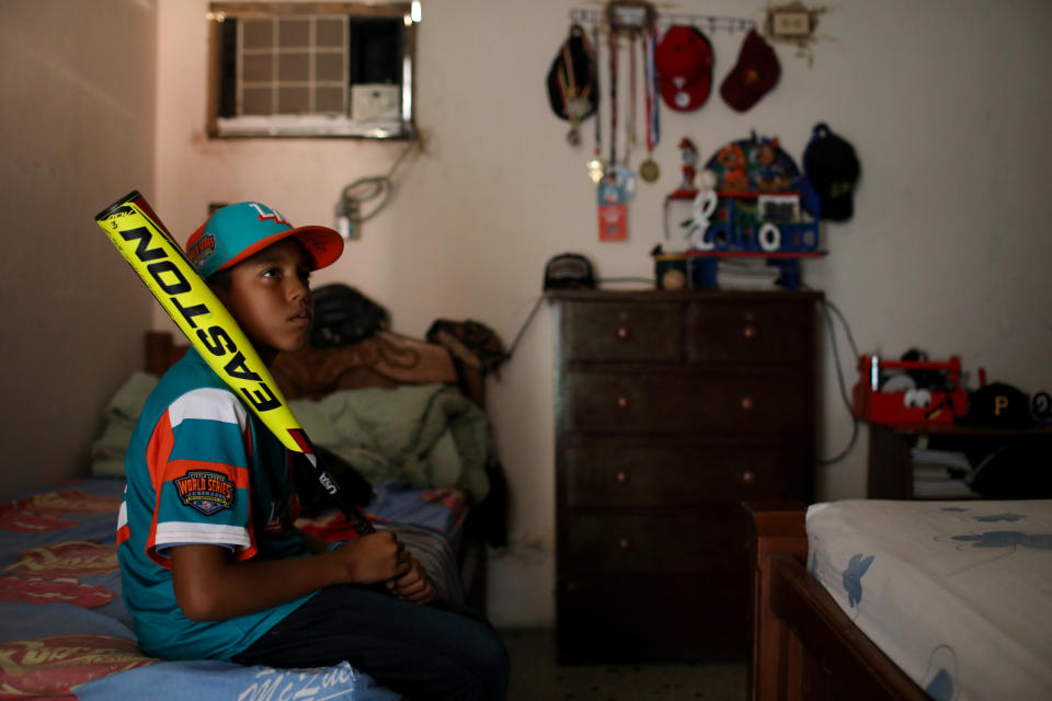 Baseball little league player Eduar Pinto, 12, poses for a photograph with a baseball bat, in his bedroom at his home in Maracaibo, Venezuela. (Photo: Manaure Quintero/Reuters)