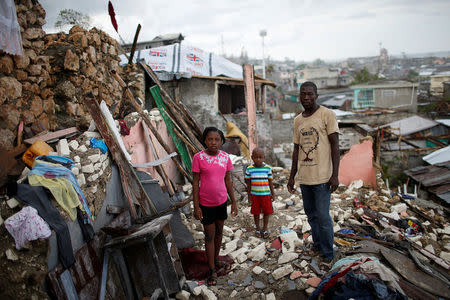 Prenille Nord, 42, poses for a photograph with his children Darline and Kervins among the debris of their destroyed house after Hurricane Matthew hit Jeremie, Haiti, October 17, 2016. "My house is completely destroyed, I have nothing left. Now we are homeless and I'm currently living in a shelter with my family but that makes no sense to me. I'm scared of the cholera. People around us are becoming sick, I really need help, so far we have not received any aid," said Nord. REUTERS/Carlos Garcia Rawlins