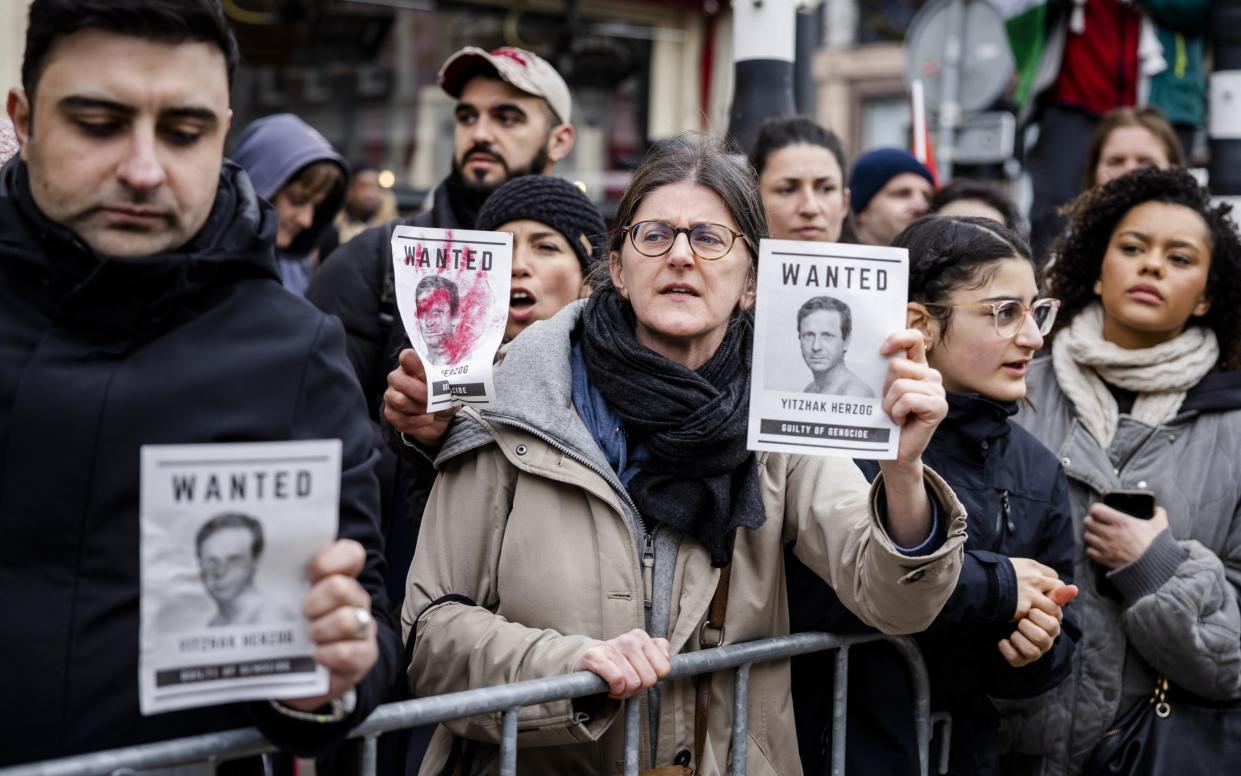 Protesters hold placards with portraits of Israeli President Isaac Herzog as they demonstrate against his presence at the opening ceremony of the National Holocaust Museum in Amsterdam