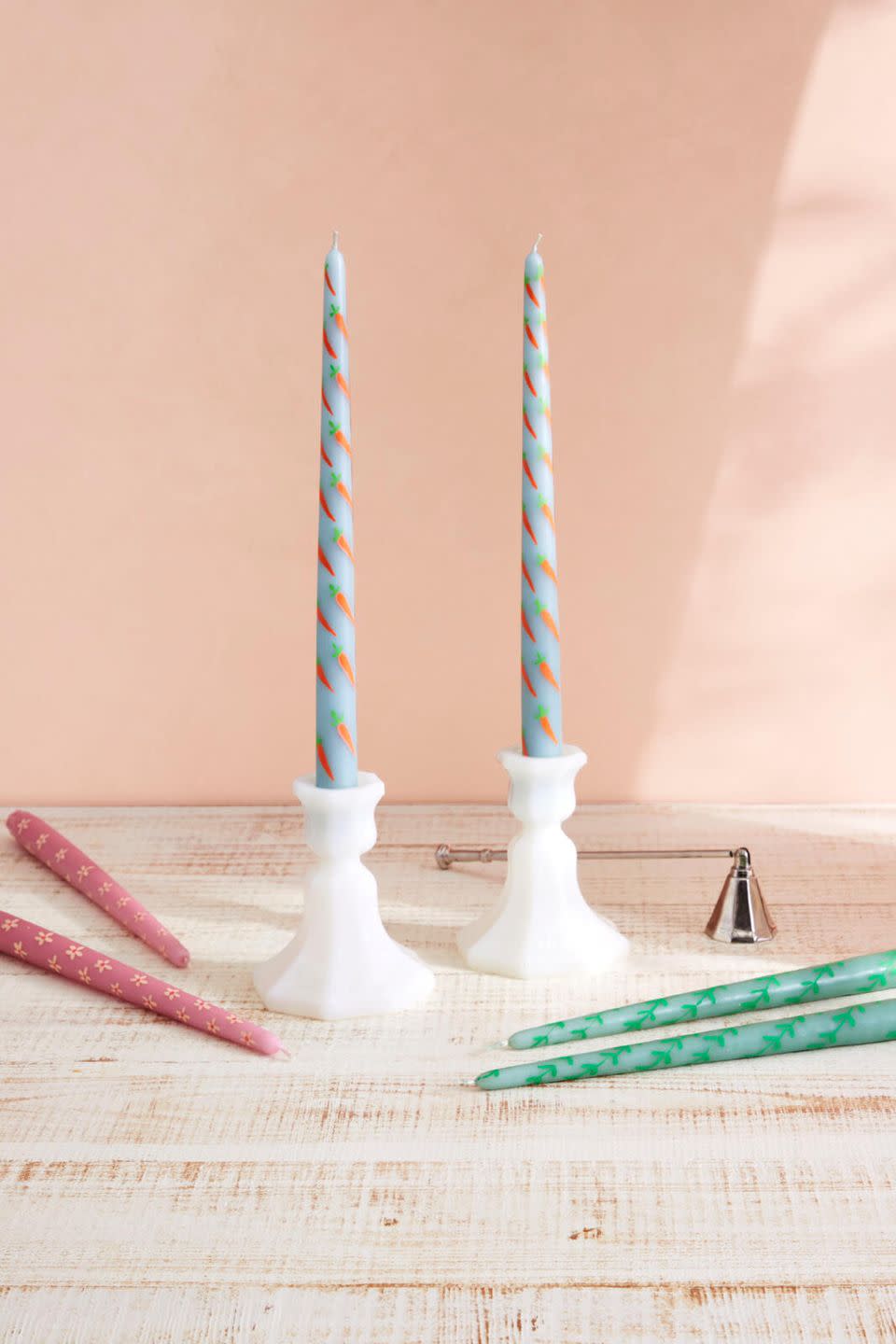 pastel colored candles painted with spring motives laying on a table or set in white candlesticks