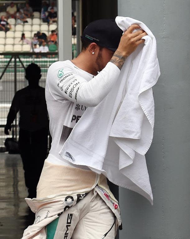 Lewis Hamilton covers himself with a towel during a rain delay in the qualifying session for the Formula One Malaysian Grand Prix in Sepang on March 28, 2015