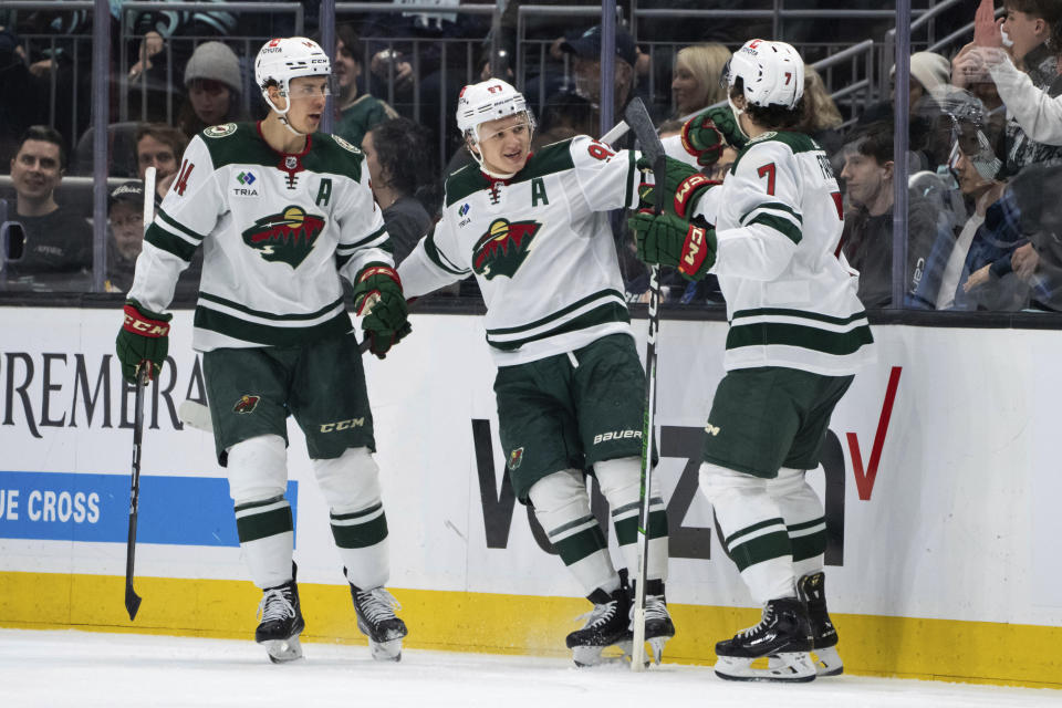 Minnesota Wild forward Kirill Kaprizov, center, forward Joel Eriksson Ek, left, and defenseman Brock Faber celebrate a goal against the Seattle Kraken during the second period of an NHL hockey game Saturday, Feb. 24, 2024, in Seattle. (AP Photo/Stephen Brashear)