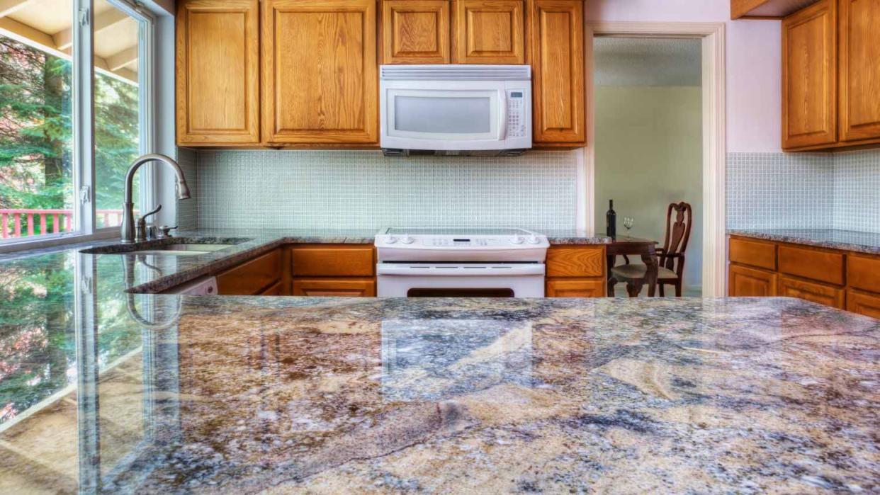 A kitchen with granite counter and  wooden cabinets