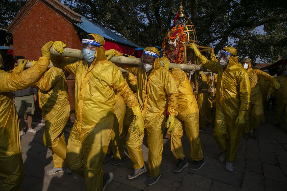 Nepalese devotees wearing protective gear as a precautionary measure against the coronavirus carry the chariot during Pachali Bhairav festival in Kathmandu, Nepal, Wednesday, Oct. 21, 2020. The festival which is usually celebrated in the night time during Dashain festival was celebrated during the day because of the pandemic. (AP Photo/Niranjan Shrestha)