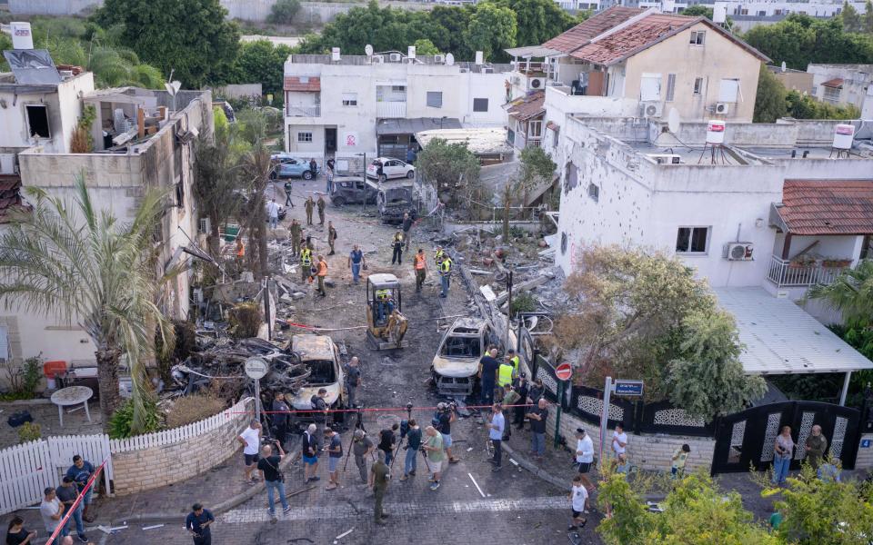 First responders, Israeli security forces and local people gather amid debris and damaged vehicles in Kiryat Bialik