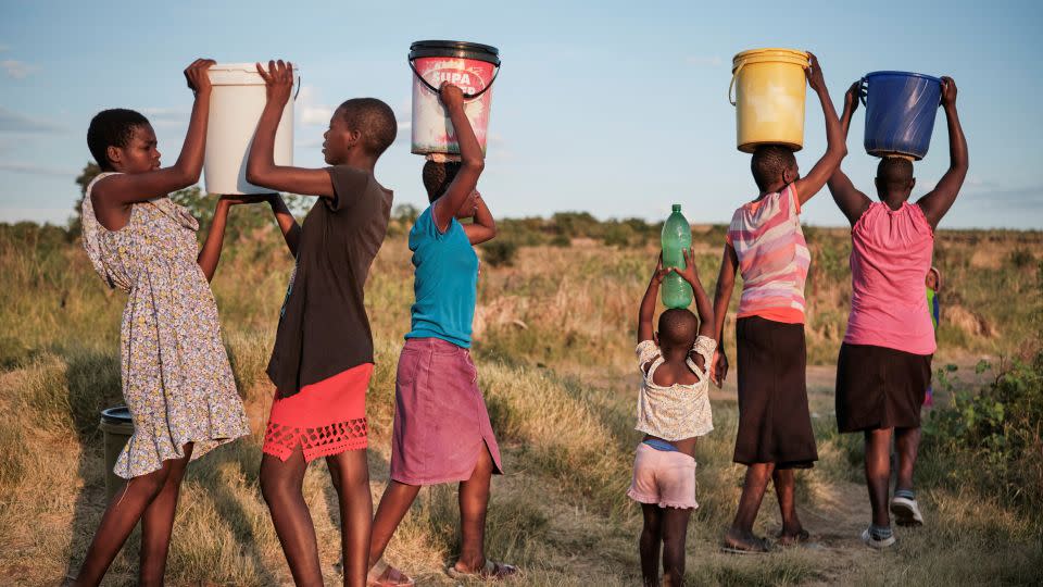 People walk home after fetching water from a well, in Pumula East township, Bulawayo, Zimbabwe on March 7, 2024. Soaring temperatures and drought are affecting large parts of the country. - Kb Mpofu/Reuters