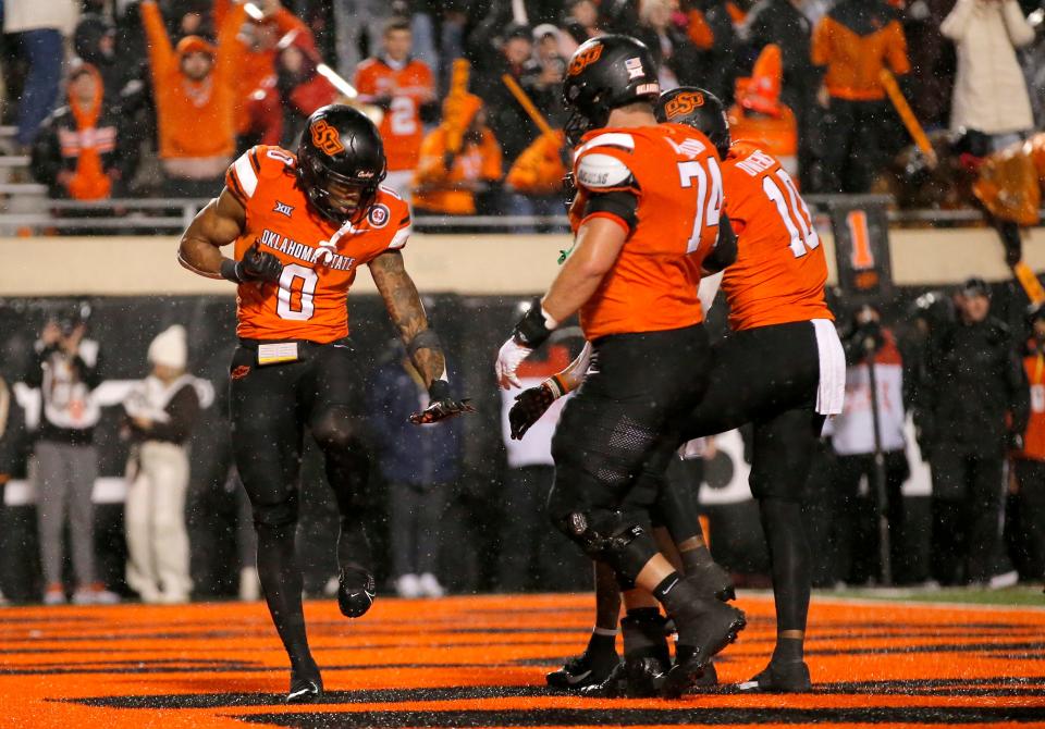 Nov 25, 2023; Stillwater, Oklahoma, USA; Oklahoma State's Ollie Gordon II (0) celebrates his touchdown with Oklahoma State's Preston Wilson (74) and Rashod Owens (10) during the second overtime of the college football game between the Oklahoma State University Cowboys and the Brigham Young Cougars at Boone Pickens Stadium. Mandatory Credit: Sarah Phipps-USA TODAY Sports
