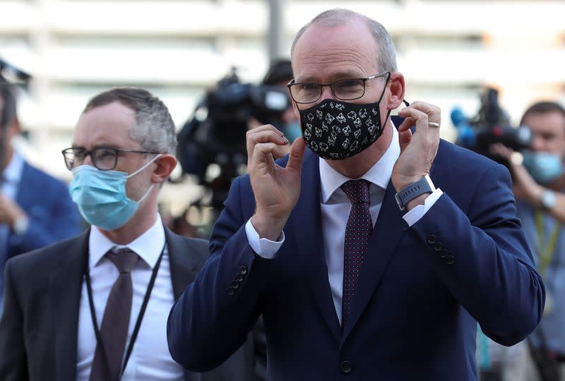 Irish Foreign Minister Simon Coveney puts on his face mask after speaking to the media, in Brussels