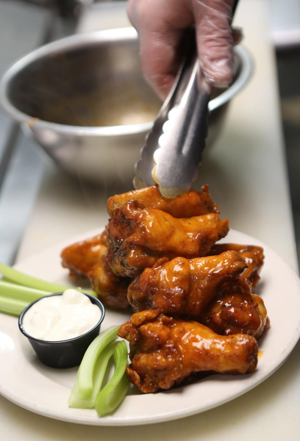 Tom Craft plates an order of chicken wings at 2 Fat Guys American Grill in Hockessin on Friday, April 12, 2024.