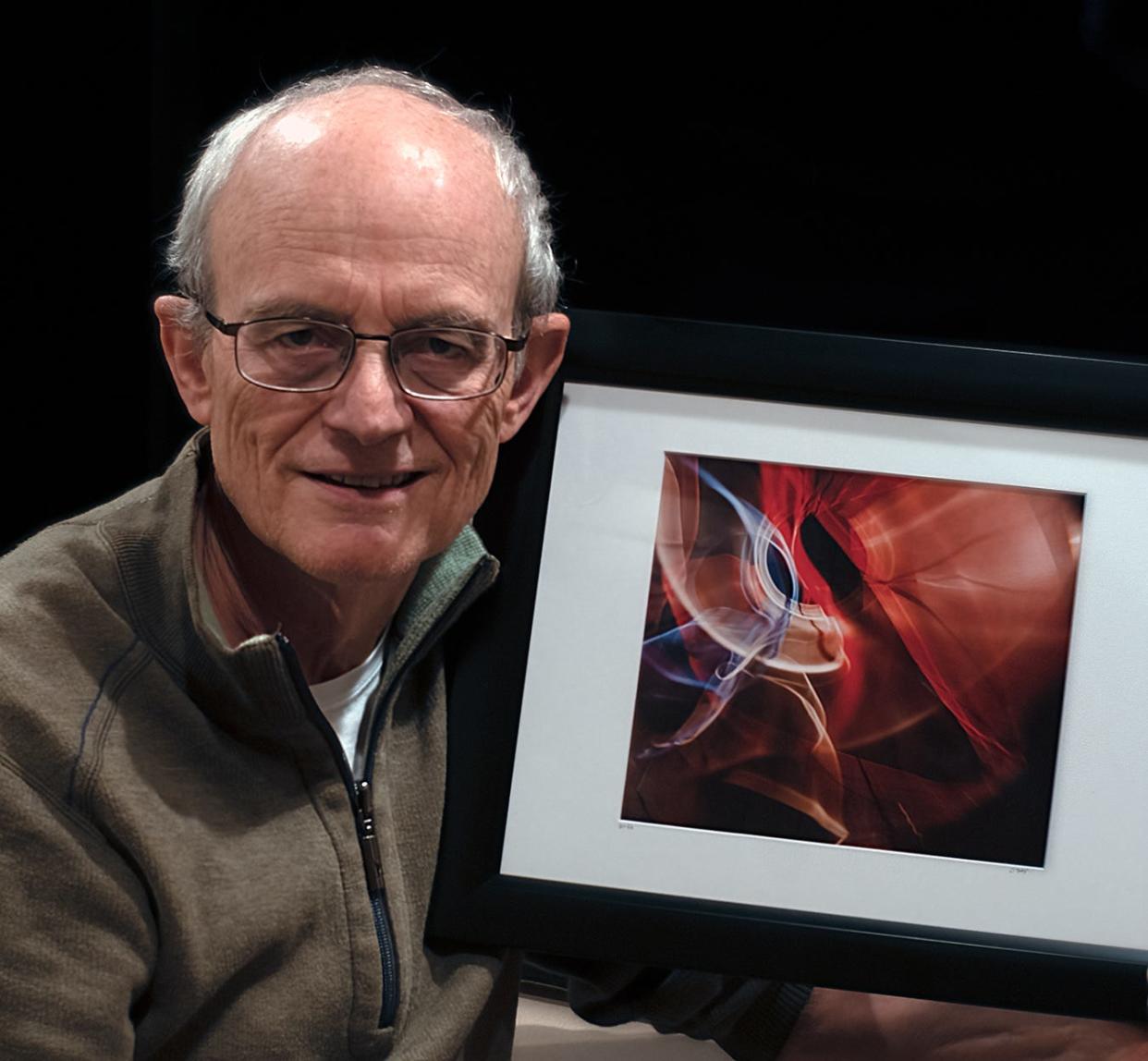 Local photographer David Day poses with one of his photos.