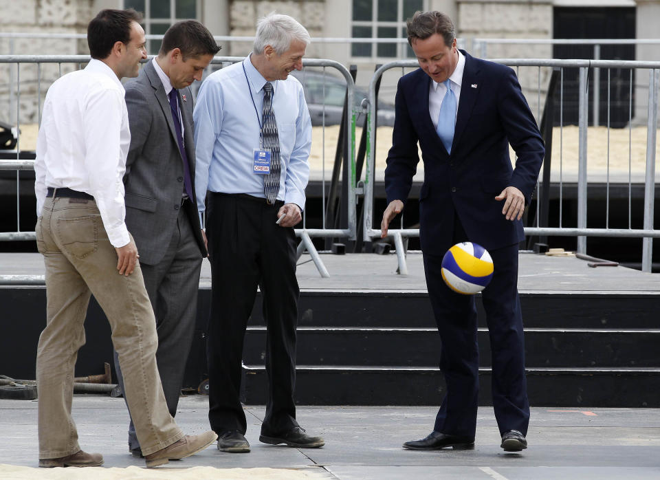 Britain's Prime Minister David Cameron (R) plays with a volleyball during a visit to the beach volleyball site for the 2012 Olympics, at Horse Guards Parade in central London, on July 27, 2011. The one-year countdown to the 2012 Olympics got under way on Wednesday with officials bullishly predicting London was on course to deliver the best ever games with 12 months to go. International Olympic Committee chief Jacques Rogge was set to extend a formal invitation to the world's athletes during a 7:00pm ceremony at Trafalgar Square in the culmination of day-long events to mark the one-year milestone.  AFP PHOTO / STEFAN WERMUTH / WPA POOL (Photo credit should read STEFAN WERMUTH/AFP/Getty Images)