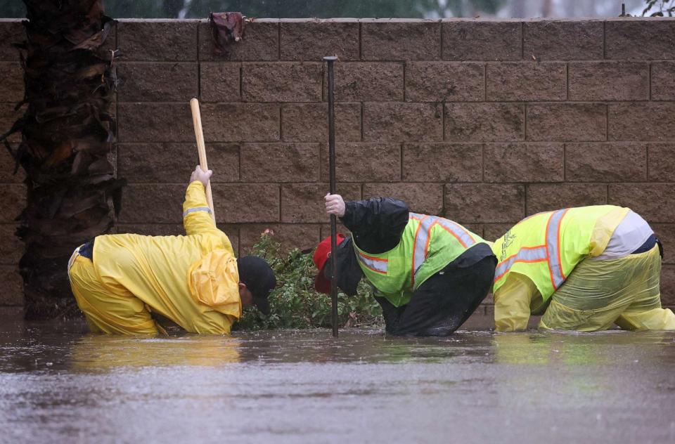 PHOTO: Workers attempt to unclog a drain on a flooded street as Tropical Storm Hilary moves through the area on Aug. 20, 2023, in Rancho Mirage, Calif. (Mario Tama/Getty Images)