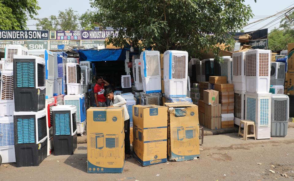 An Indian worker displays air coolers for sale as the temperature rises in New Delhi, 28 April 2022 (EPA)