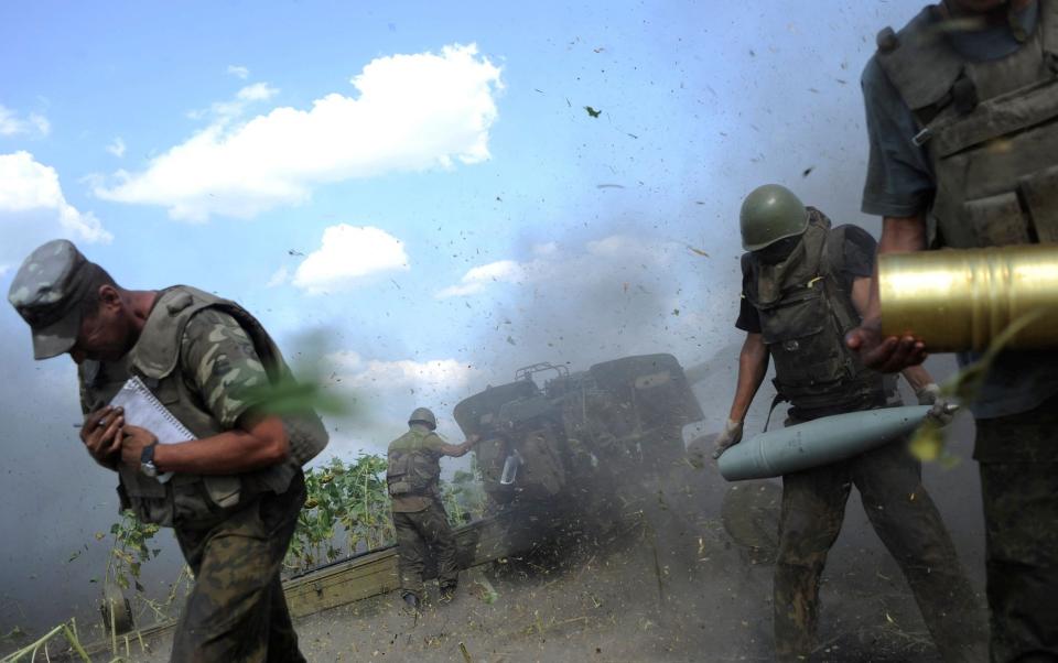 Ukrainian servicemen take cover after firing a canon during a military operation in near Pervomaisk, Luhansk region - MAKSIM LEVIN 