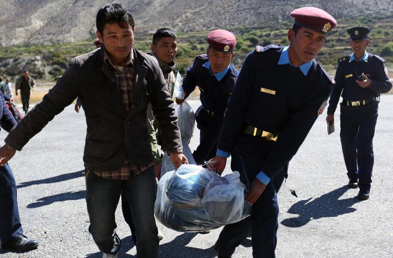 Nepalese police move the bodies of trekkers killed in a snowstorm to be flown to Kathmandu on October 17, 2014 in Jomsom