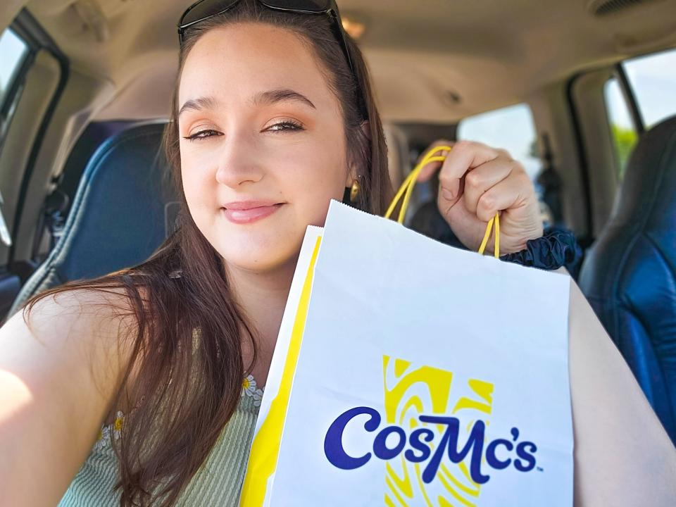 Photo of the writer wearing a green tank top and sunglasses on her head holding a white bag with blue and yellow CosMc's logo