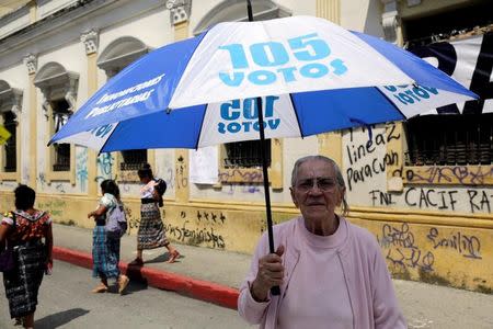 A woman holds an umbrella with the writing "105 votes" during a protest against Guatemala's President Jimmy Morales outside congress, in Guatemala City, Guatemala September 10, 2017. REUTERS/Luis Echeverria