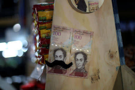 Venezuelan hundred bolivars bills are seen on a pole in La Vega market in Santiago, Chile, May 10, 2018. Picture taken May 10, 2018. REUTERS/Ivan Alvarado