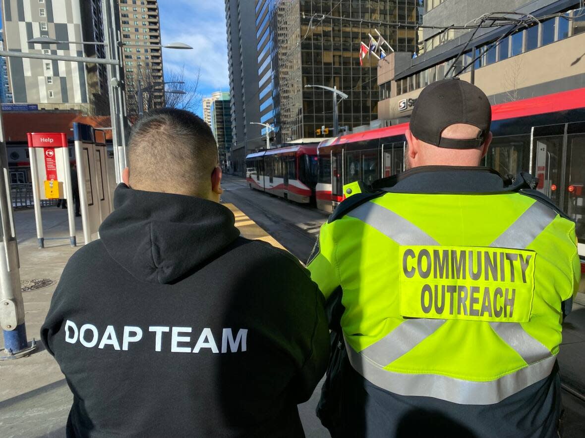 Two members of Alpha House's DOAP team survey the CTrain tracks on Seventh Avenue S.W. in downtown Calgary'. (Alpha House - image credit)