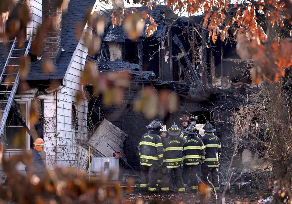 Firefighters gather around a burned out section of a home after they extinguished the flames of house fire on Monday, Feb. 19, 2024 in Ferguson, Mo. A mother and four children died early Monday as police say the fire is being investigated as "suspicious." (David Carson/St. Louis Post-Dispatch via AP)