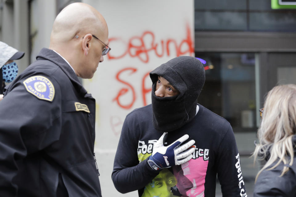 Demonstrator Keith Brown, right, talks with Seattle Fire Dept. Assistant Chief Willie Barrington as they plan to remove makeshift barricades protesters had put up in the streets next to a Seattle police precinct Tuesday, June 9, 2020, in Seattle, following protests over the death of George Floyd. Floyd, a black man died after being restrained by Minneapolis police officers on May 25. (AP Photo/Elaine Thompson)