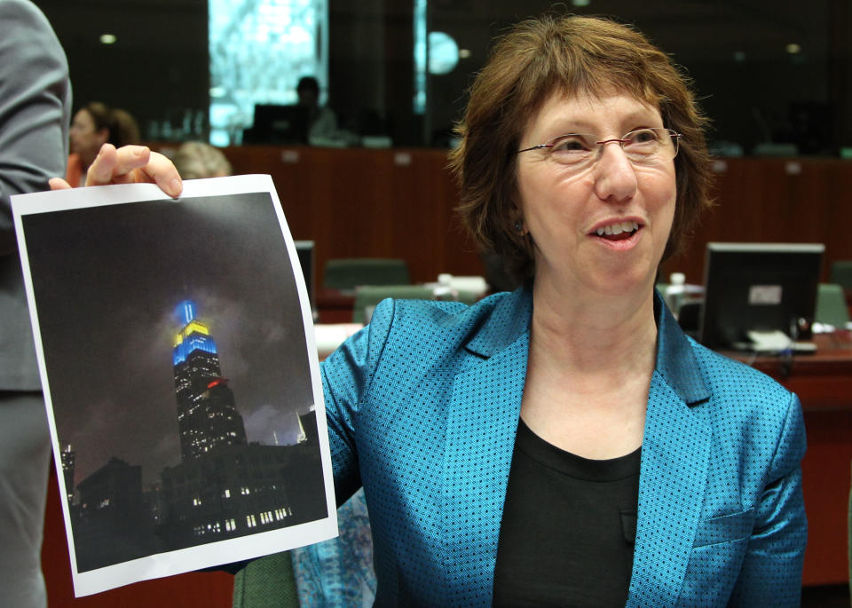 EU foreign policy chief Catherine Ashton shows a photo of the Empire State building in New York, that was lighted up for Europe day, in the European Union's flag colors, prior to the start of an EU foreign affairs meeting at the European Council building in Brussels, Monday, May 14, 2012. (AP Photo/Yves Logghe)