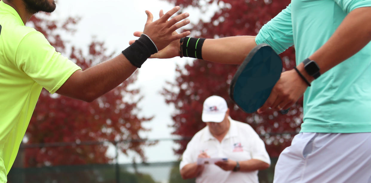 Two pickleball tournament players shake hands after a match.