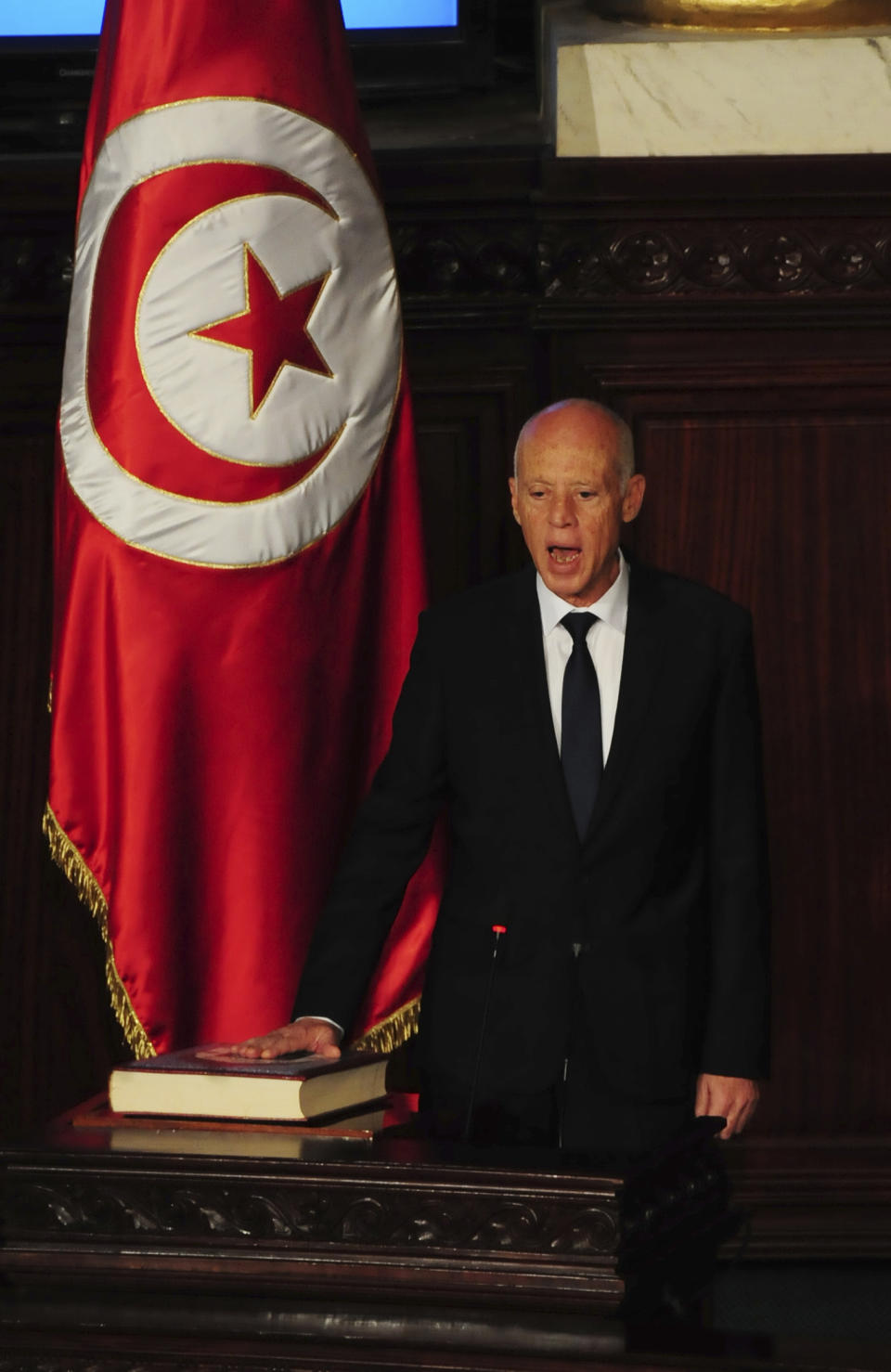 Newly elected Tunisian President Kais Saied puts his hand on the Quran to be sworn in as Tunisian President , in Tunis, Wednesday Oct.23, 2019. Tunisians elected former law professor Kais Saied as president earlier this month to replace President Beji Caid Essebsi, who died in July. (AP Photo/Hassene Dridi)