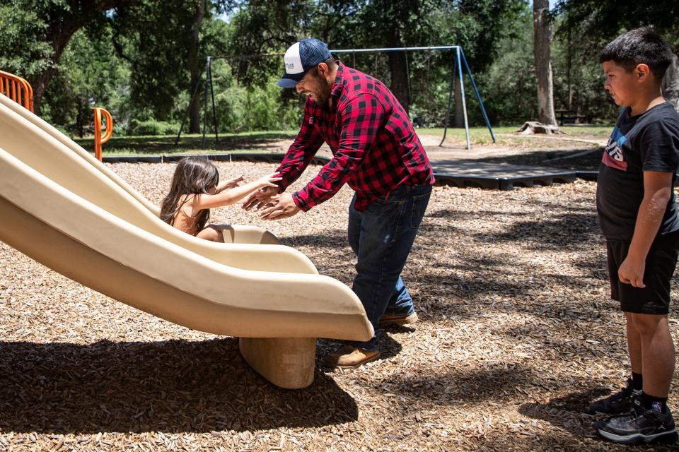 Seth Doria, 9, watches his father, Jamie Martinez, help Gianna Martinez, 3, off a slide at Memorial Park in Uvalde, Texas, on May 25, 2022. Martinez removed his son Seth from Robb Elementary  before a gunman killed 21 people, including children. "Those kids were part of his class," Martinez said. "All (Seth) knows is he lost some friends."