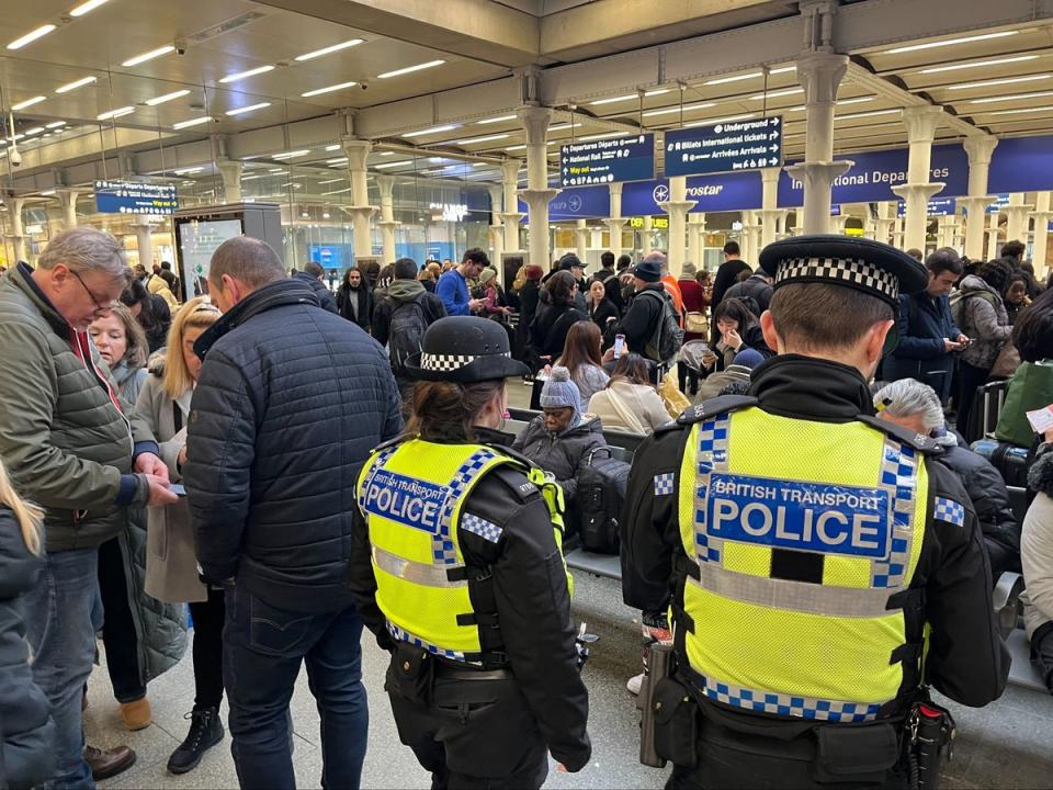 British Transport Police officers watch as passengers wait at the Eurostar entrance in St Pancras (PA)