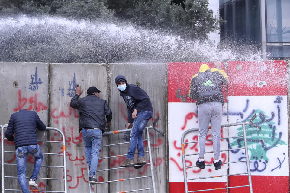 Anti-government protesters climb a concrete installed by authorities to block a road that links to the parliament building during a protest against the new government, in downtown Beirut, Lebanon, Tuesday, Feb. 11, 2020. (AP Photo/Bilal Hussein)