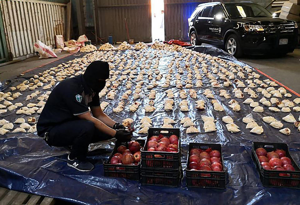 FILE - In this photo released by Saudi Press Agency, a Saudi custom officer opens imported pomegranates, as customs foiled an attempt to smuggle over 5 million pills of an amphetamine drug known as Captagon, which they said came from Lebanon, at Jiddah Islamic Port, Saudi Arabia, April 23, 2021. Lebanon has been without a president for over a month, its legislators unable to agree on a new head of state. Saudi Arabia banned agricultural exports from Lebanon, nominally due to shipments being used to smuggle drugs, and later in 2021 banned all Lebanese exports after a minister called Saudi Arabia’s war in Yemen “absurd.” (Saudi Press Agency via AP, File)