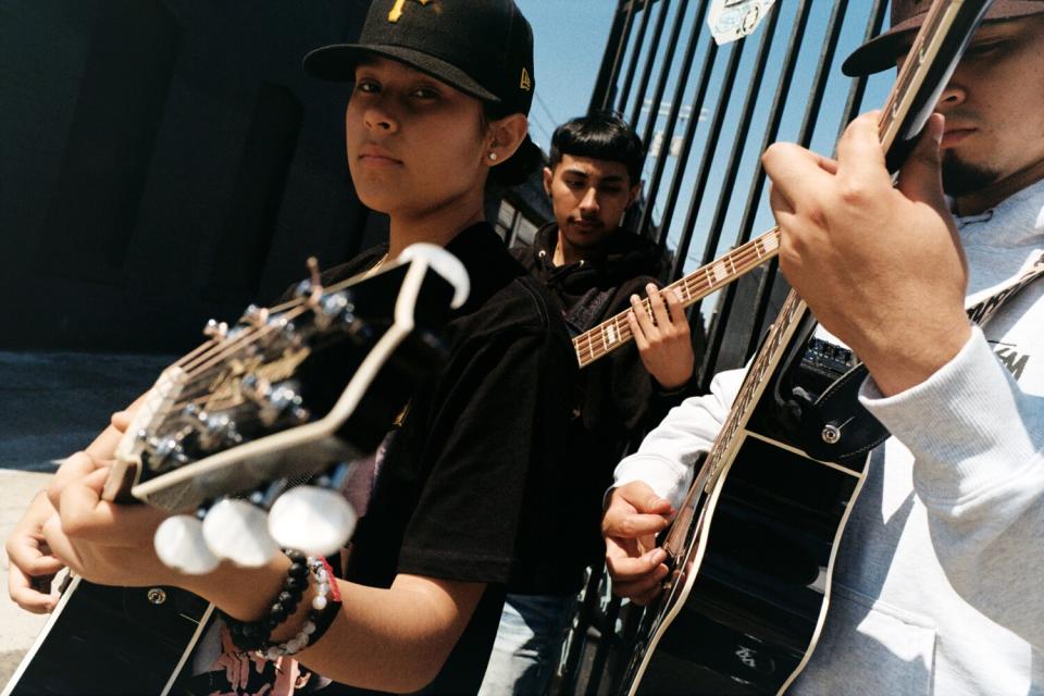 Three people play music outside.