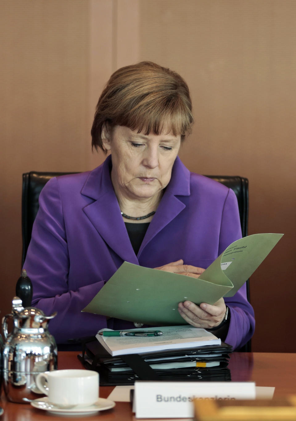 German Chancellor Angela Merkel reads in her documents after arriving for the weekly cabinet meeting at the chancellery in Berlin, Germany, Wednesday, April 2, 2014. (AP Photo/Markus Schreiber)