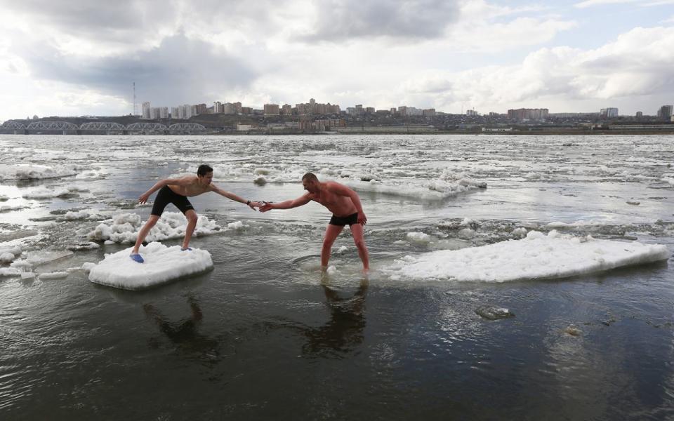 <p>Mitglieder des „Yenisei Walrösser“-Schwimmteams steigen während eines Eisgangs am Fluss Jenissei im russischen Krasnojarsk von einer Eisscholle auf die andere. (Bild: Ilya Naymushin/Reuters) </p>