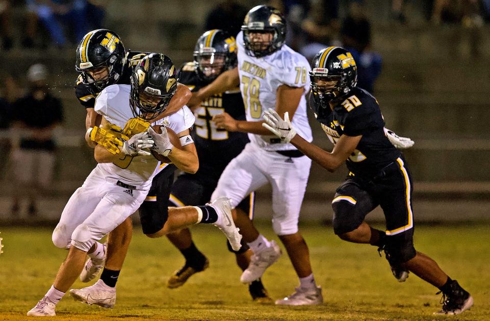 The Menard defense brings down a player rushing the ball for Junction on Friday, Oct. 9, 2020.