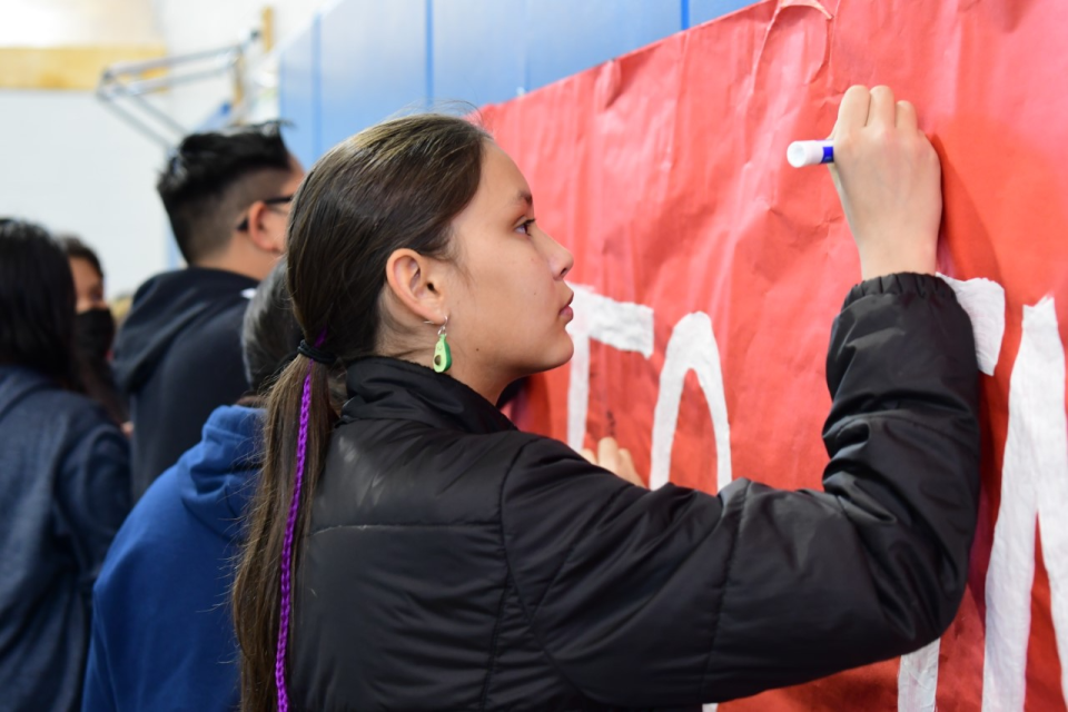 Kirtland Central Elementary student Athena Naranjo signing the #ChooseToInclude banner along with other students in the gymnasium in preparation for the upcoming CCSD Special Olympics.