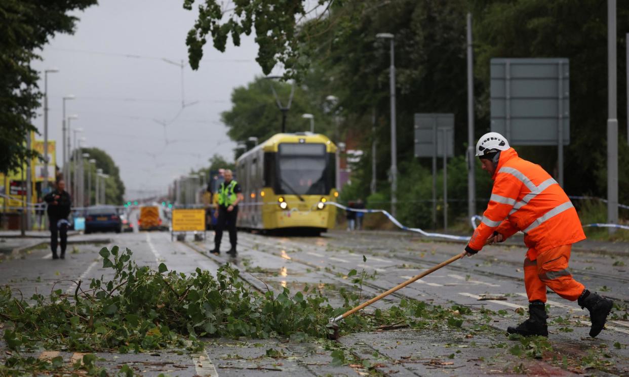 <span>Workers begin to remove fallen tree branches blocking roads and tram routes in Manchester.</span><span>Photograph: Phil Noble/Reuters</span>